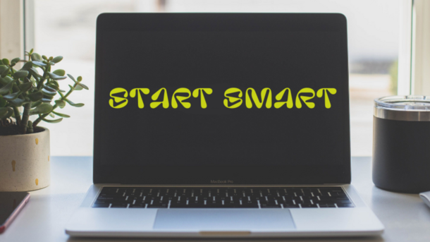 Ein Laptop steht aufgeklappt auf dem Schreibtisch. Auf dem Bildschirm steht "Start Smart".