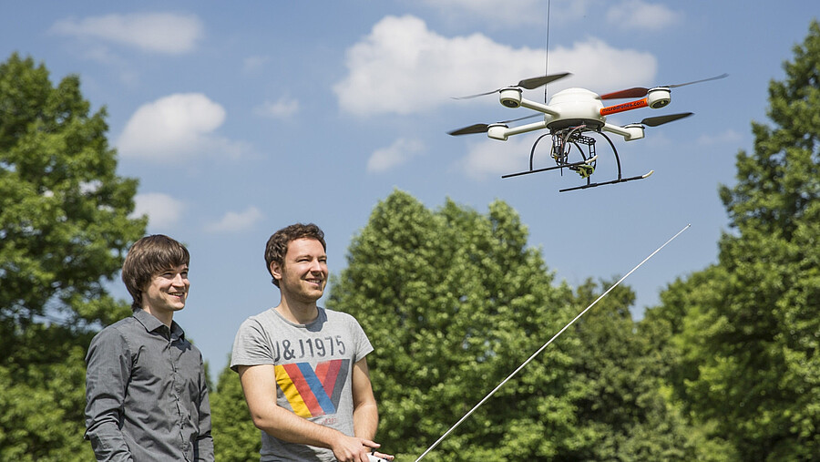 Two men control a drone.